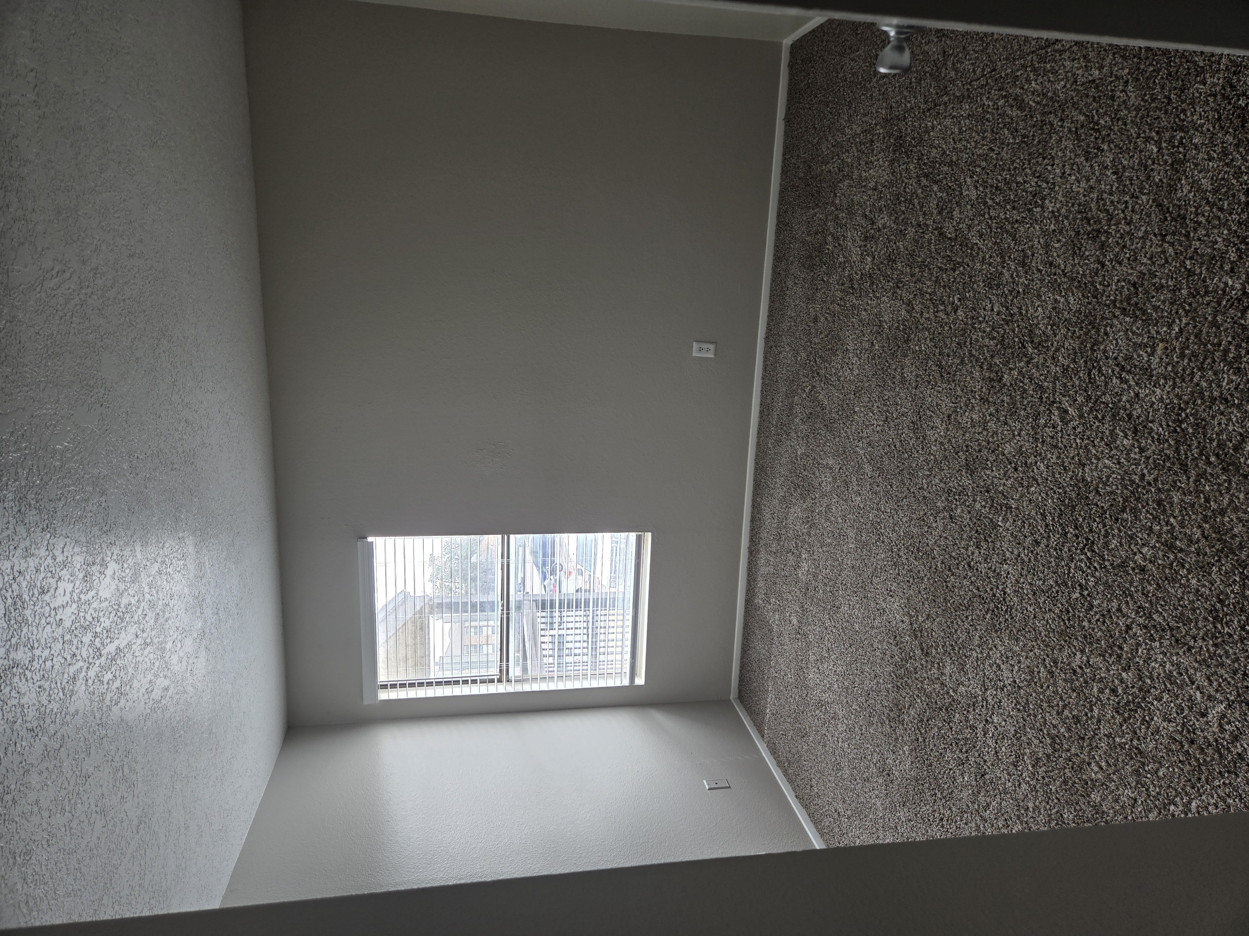 A room with a window and a wall with a speckled pattern.